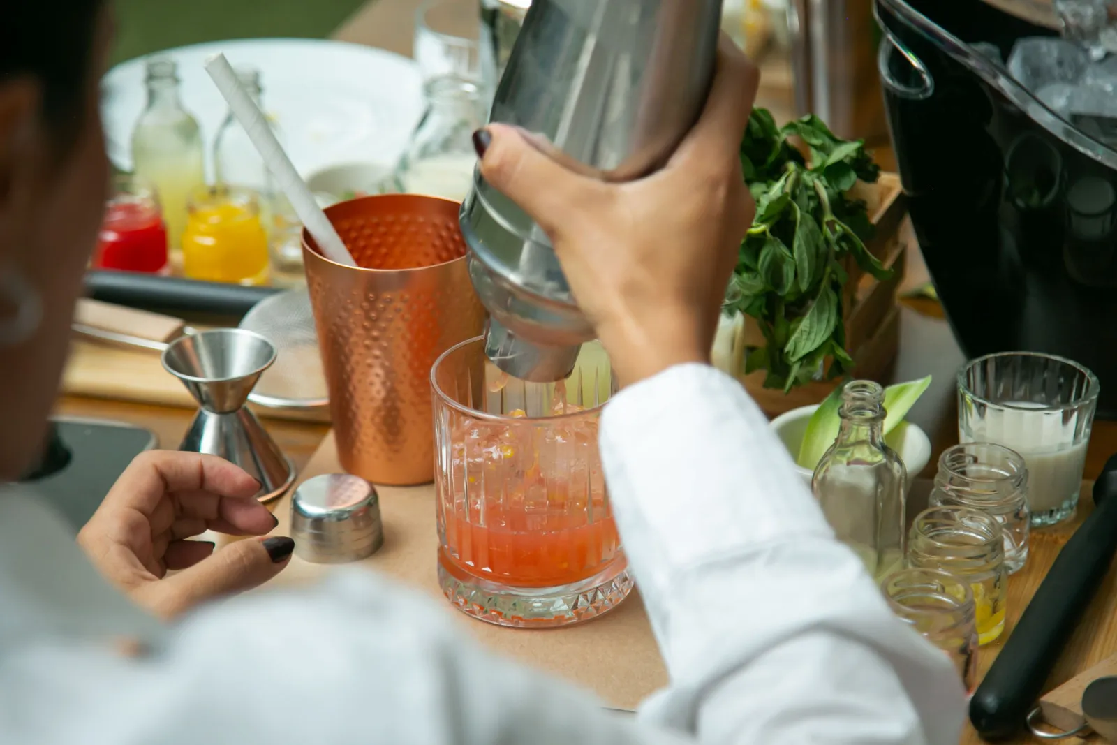 Person taking part in mixing drink as part of cocktail making course at office christmas party